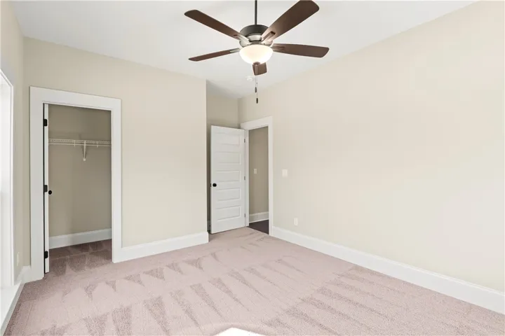 A quiet retreat with plush carpeting and a modern ceiling fan, offering a comfortable personal space.