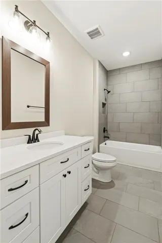 A refined bathroom features a bright white vanity with a sleek countertop, paired with stylish gray tile flooring.