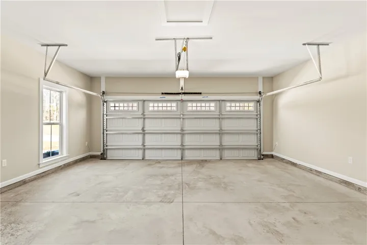 A spacious, pristine garage featuring a modern automatic door and bright window.