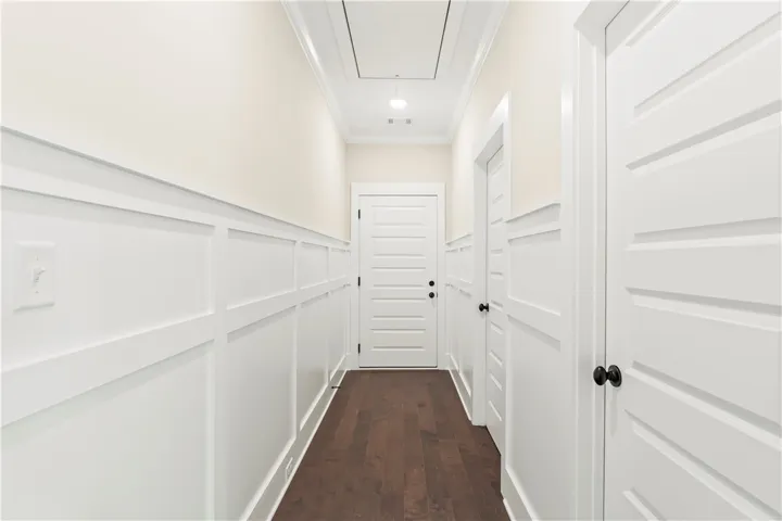 Rich hardwood floors complement elegant wainscoting and crown molding throughout this inviting hallway.
