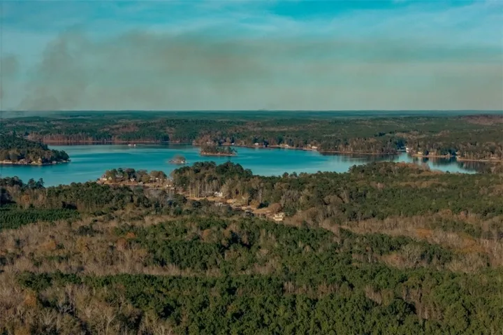 Discover expansive forested acreage bordering a serene lake, offering unparalleled natural beauty and privacy.