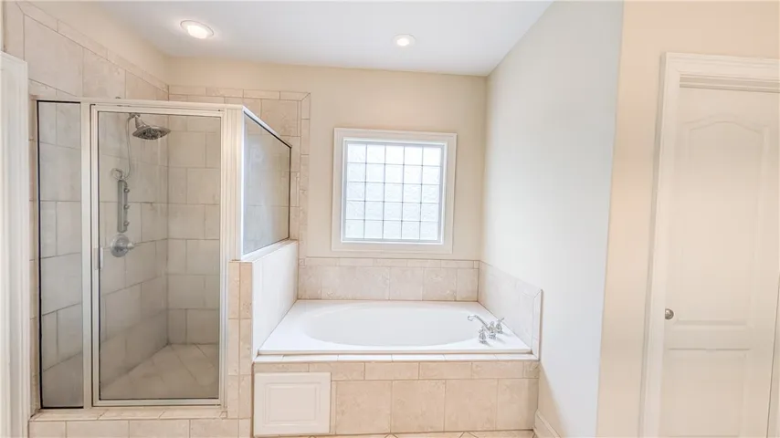 Lux primary bath features a relaxing jetted tub, tiled step-in shower, dual vanities, and water closet.