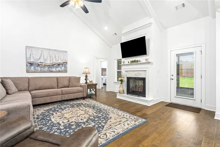 Hardwood floors and a grand fireplace create a welcoming focal point in this well-lit living space.