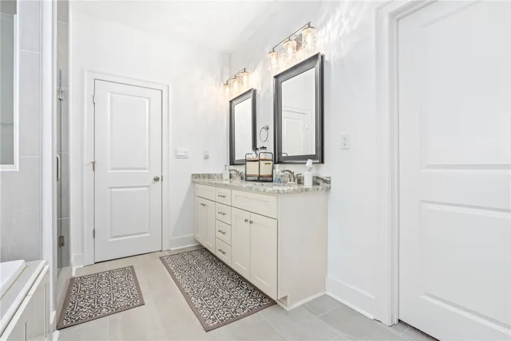 Dual vanities with stone counters enhance this well-appointed bathroom.