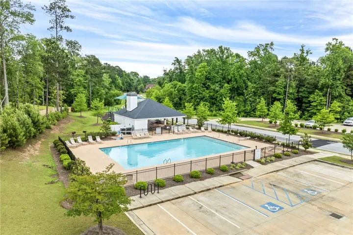 An inviting community pool awaits, nestled beside a charming clubhouse amidst lush green landscaping.