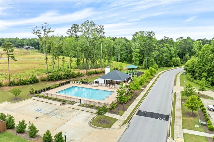 An aerial view captures the community pool, adjacent parking, and scenic natural surroundings.