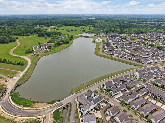 An aerial perspective reveals a serene lake nestled amongst a vibrant community, offering water views to many homes.