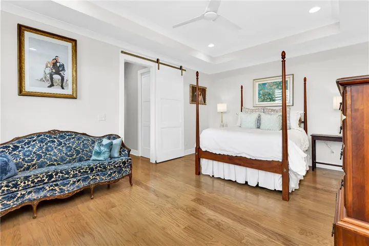 Hardwood floors and tray ceilings elevate this bright, spacious primary bedroom.