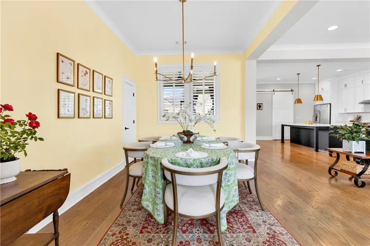 Elegant dining space, showcasing a stylish chandelier and abundant natural light, seamlessly transitions to a modern kitchen.