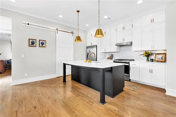 A well-lit kitchen featuring a spacious island, gleaming hardwood floors, and modern fixtures.