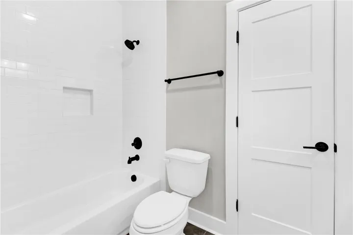 A well-appointed bathroom with a sleek white tiled shower and modern black fixtures.