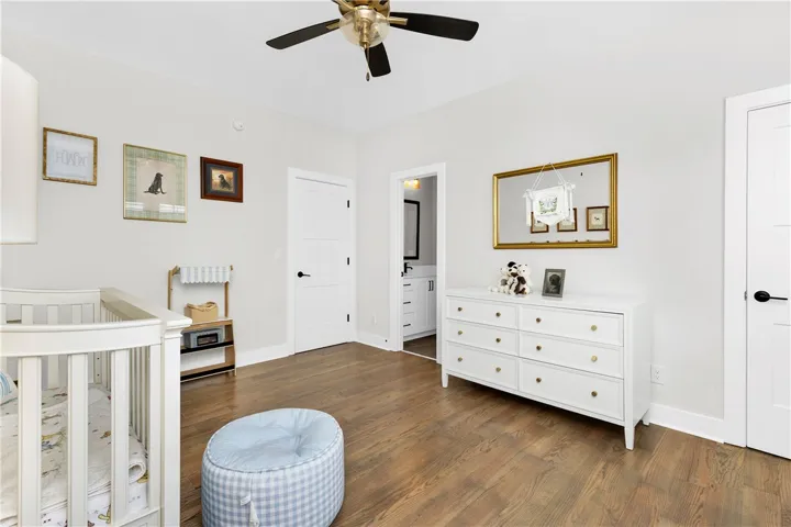 Hardwood floors and a ceiling fan enhance this cozy bedroom with direct bathroom access.