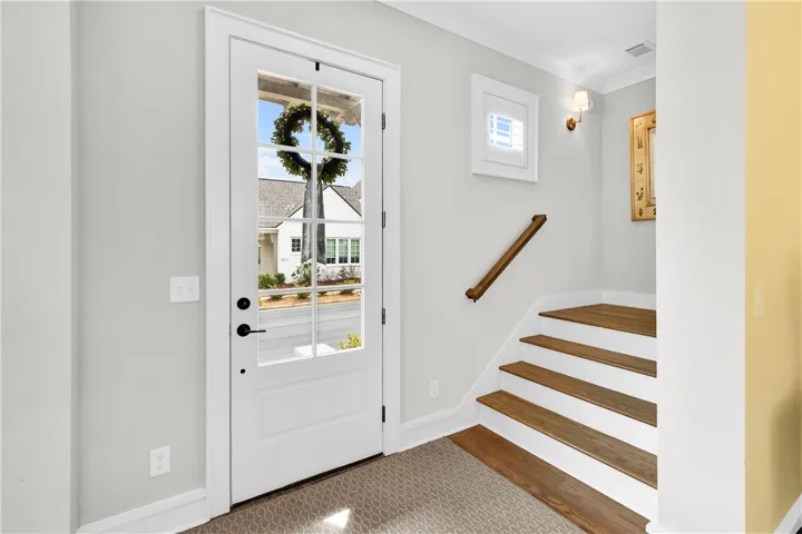 A welcoming entry featuring a charming glass-paned door and elegant hardwood stairs.
