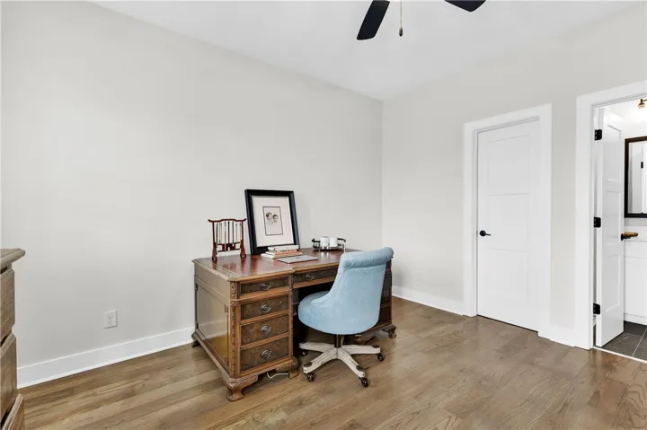 Hardwood flooring extends throughout this versatile space, ideal for an office or study.