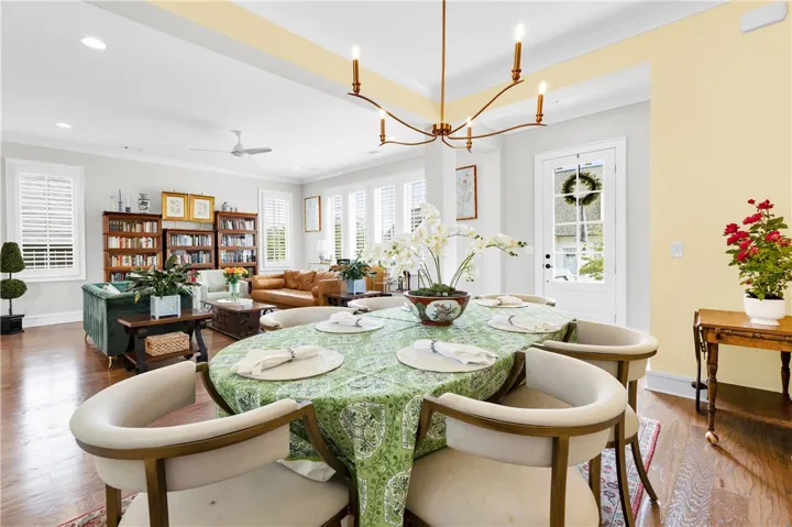 Hardwood floors stretch across this inviting open-concept space, merging dining and living areas under tasteful lighting fixtures.