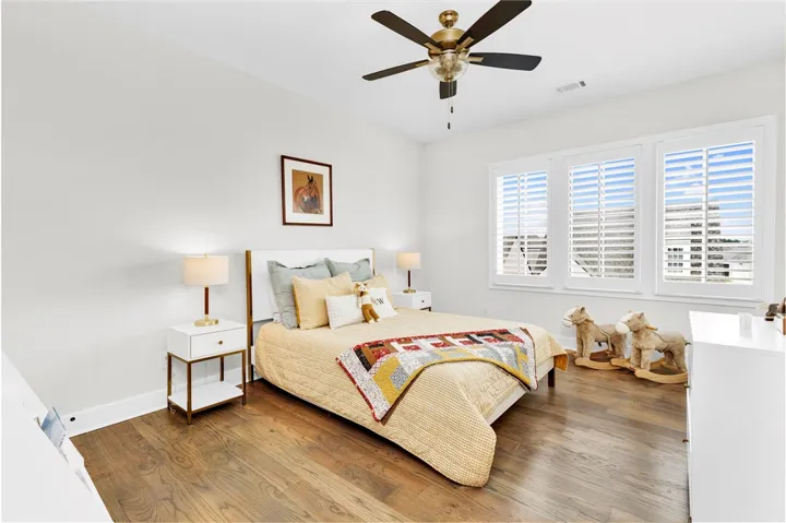 Hardwood floors and bright windows create an inviting, naturally illuminated bedroom retreat.