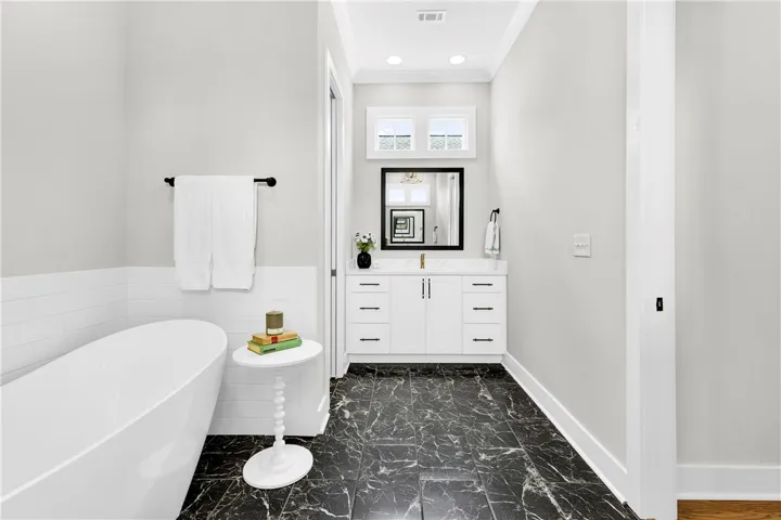 A freestanding soaking tub complements a stylish vanity with a sleek mirror in this elegant bathroom.