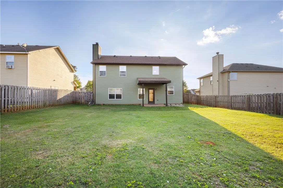 This spacious backyard offers privacy and room for recreation, featuring a covered patio for outdoor enjoyment.