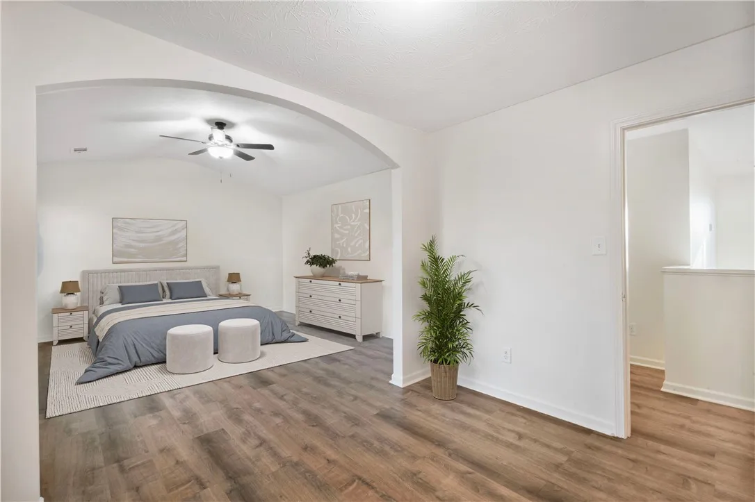 An inviting sleeping area features an arched entryway and high ceilings with a ceiling fan.