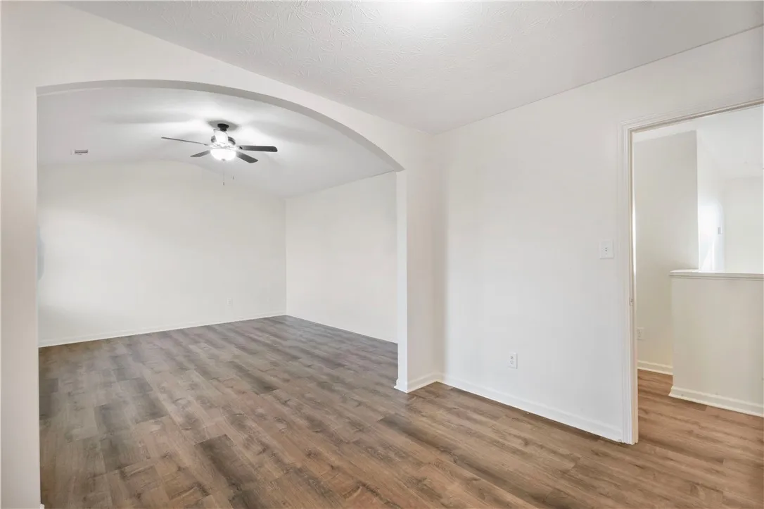 This airy room features a vaulted ceiling, durable LVP flooring, and an elegant arched entryway.