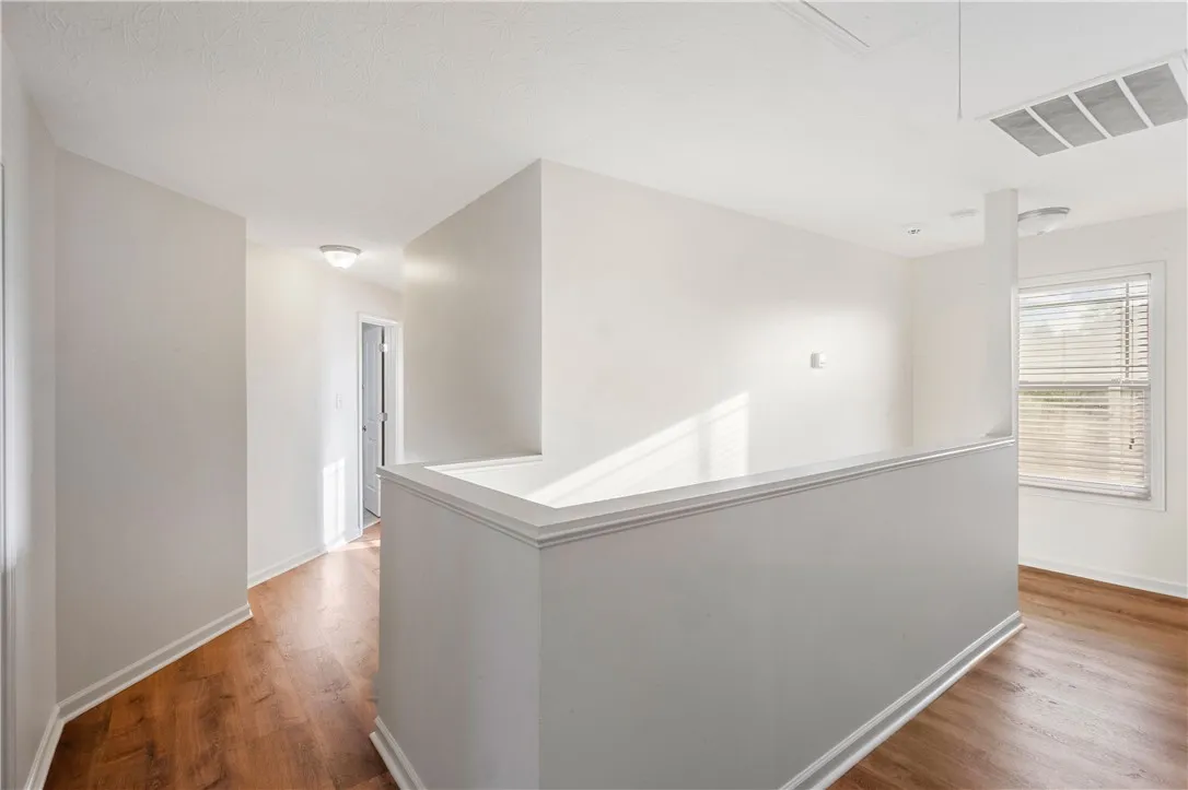This bright hallway offers warm LVP flooring and abundant natural light through window blinds.