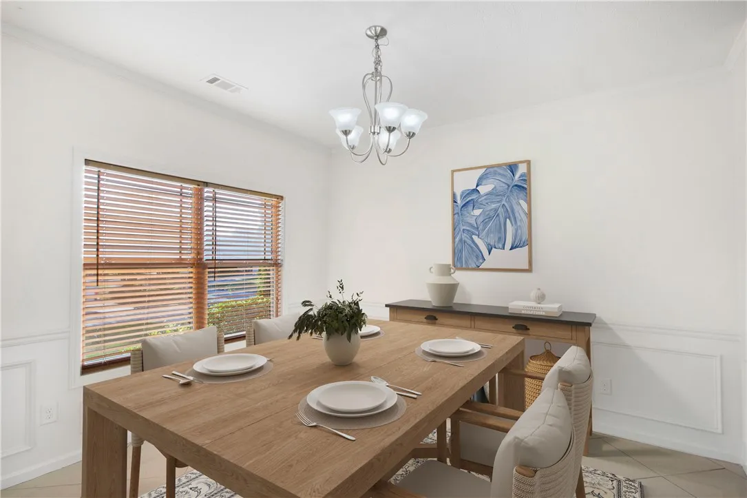 A well-lit dining area featuring a modern light fixture and rich wood blinds for privacy.