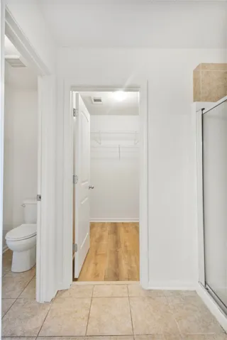 This functional bathroom features practical flooring, a toilet, and an accessible walk-in closet for everyday convenience.