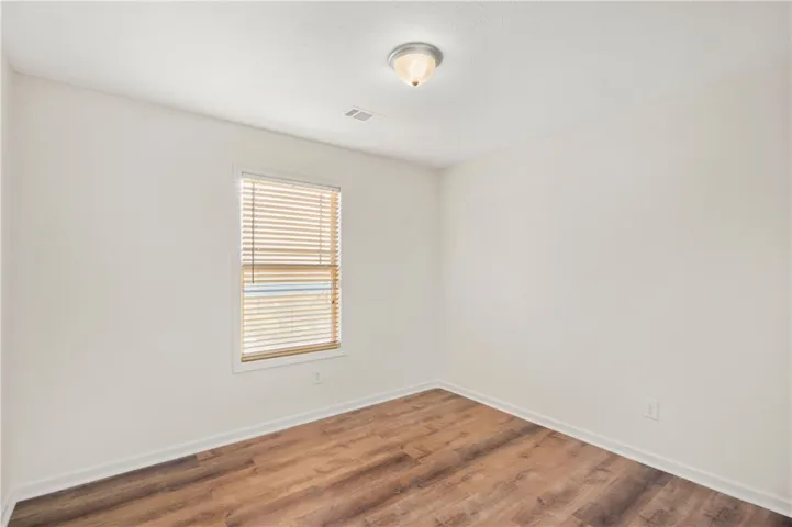 This spacious room features ample natural light and durable flooring, offering a comfortable living space.