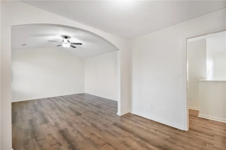 This airy room features a vaulted ceiling, durable LVP flooring, and an elegant arched entryway.