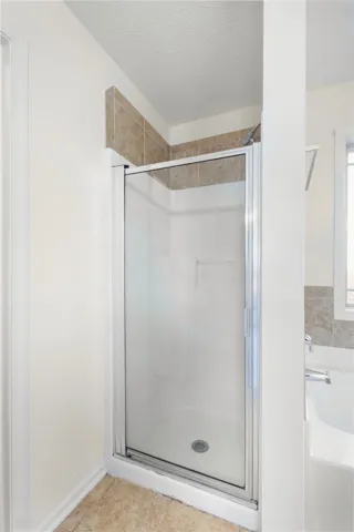 This bright bathroom features a clear glass shower and a cozy bathtub, ready for relaxation.