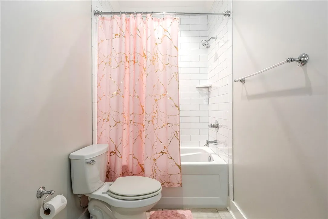 A pristine bathroom features a classic shower-over-tub design with bright white subway tile, ensuring a crisp, clean aesthetic.