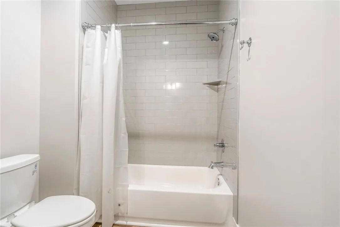 A well-maintained bathroom featuring a classic bathtub with subway tile surround and a convenient shower.