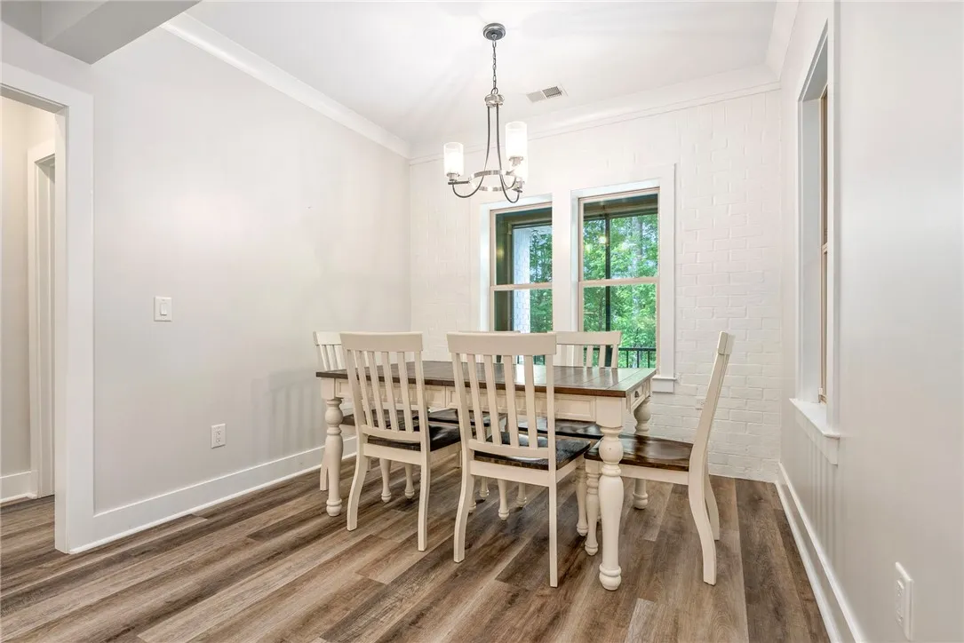 Natural light floods this dining area, featuring stylish wide plank flooring and a contemporary chandelier.