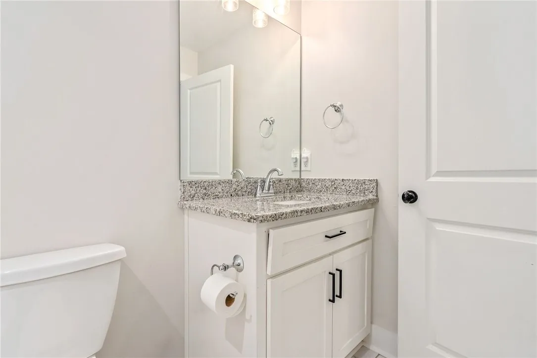 A well-appointed half-bath offers convenience and a sleek granite vanity.