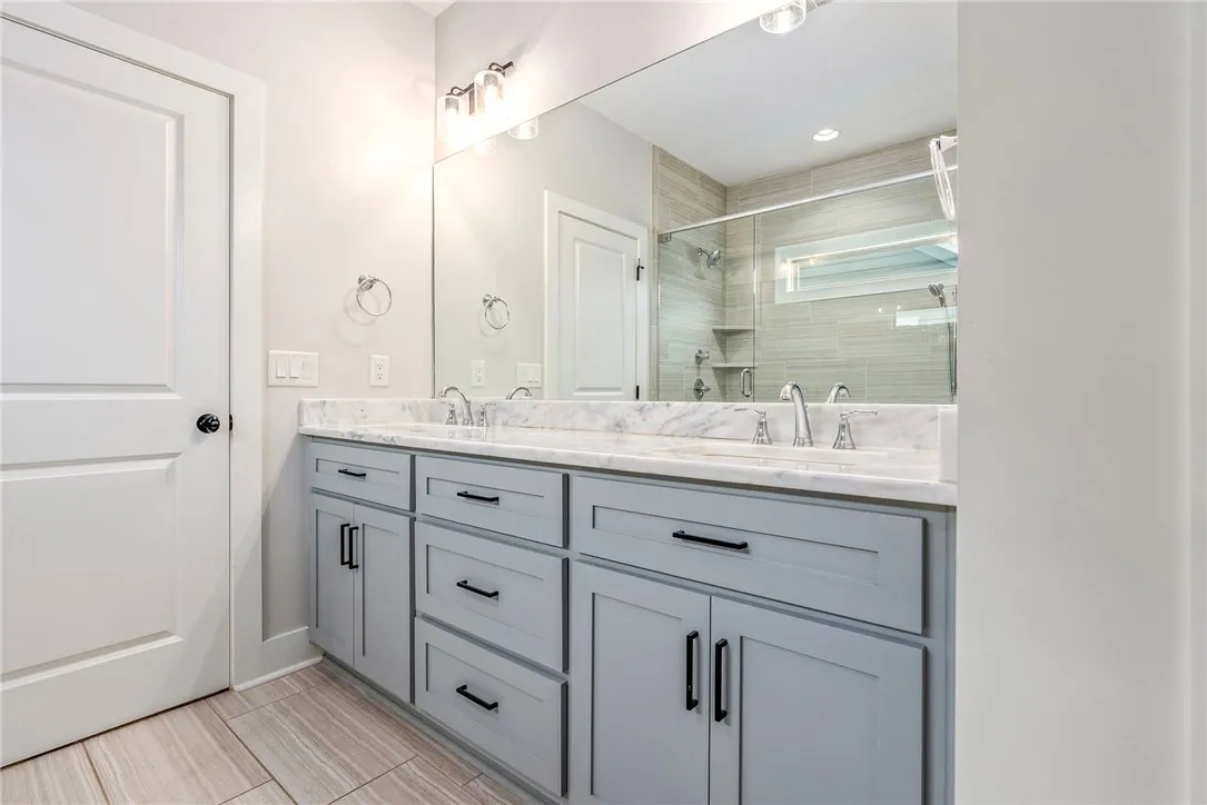 Marble double vanity and a glass-enclosed shower create a practical bathroom retreat.