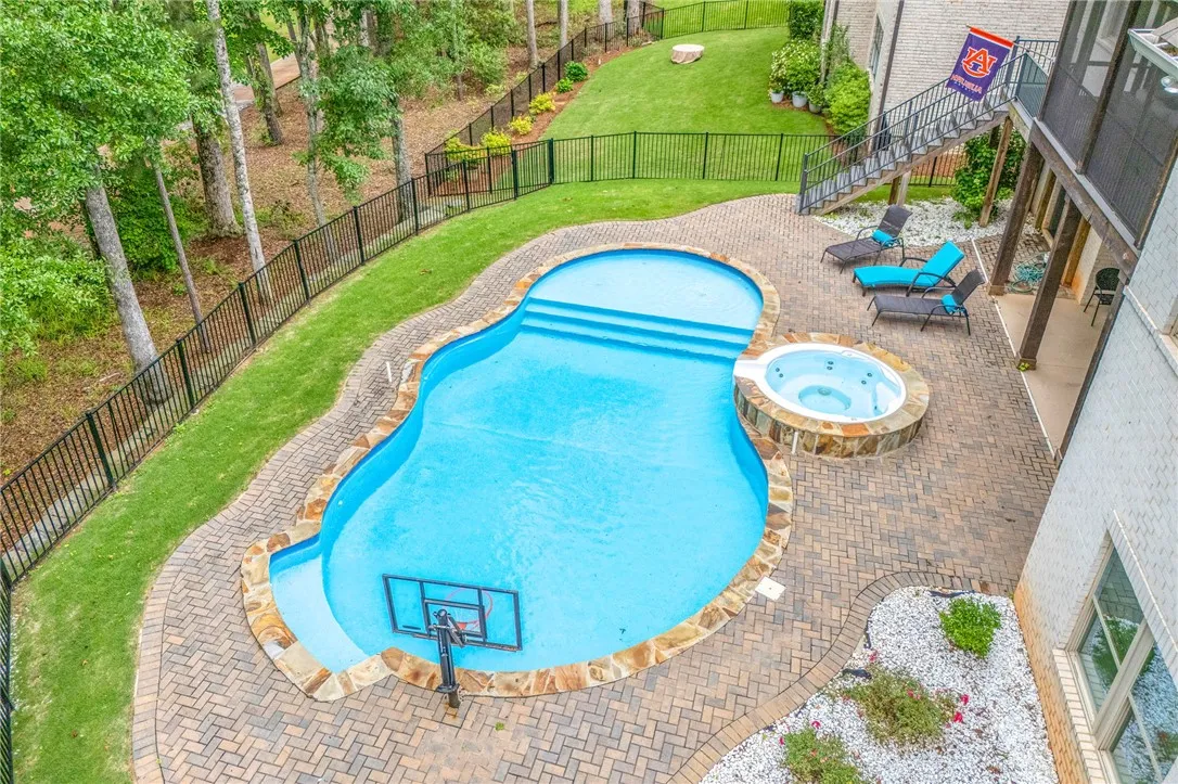 An inviting backyard oasis offers a free-form pool and integrated spa, surrounded by paver patio and verdant lawn.
