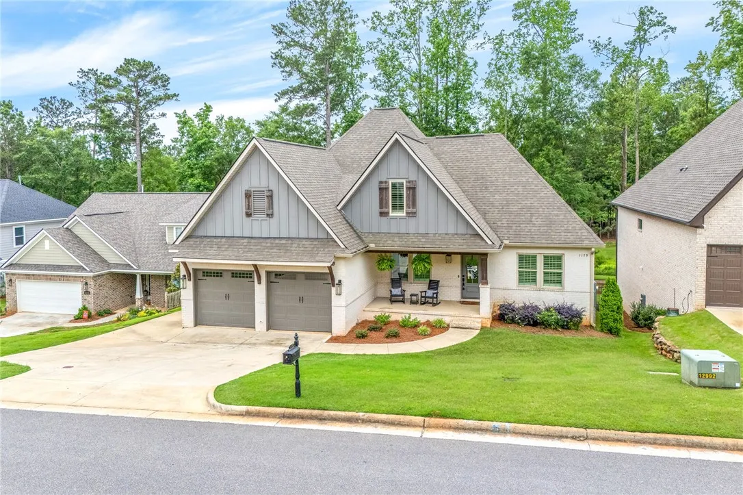 A charming residence with a covered front porch and lush green landscaping awaits.