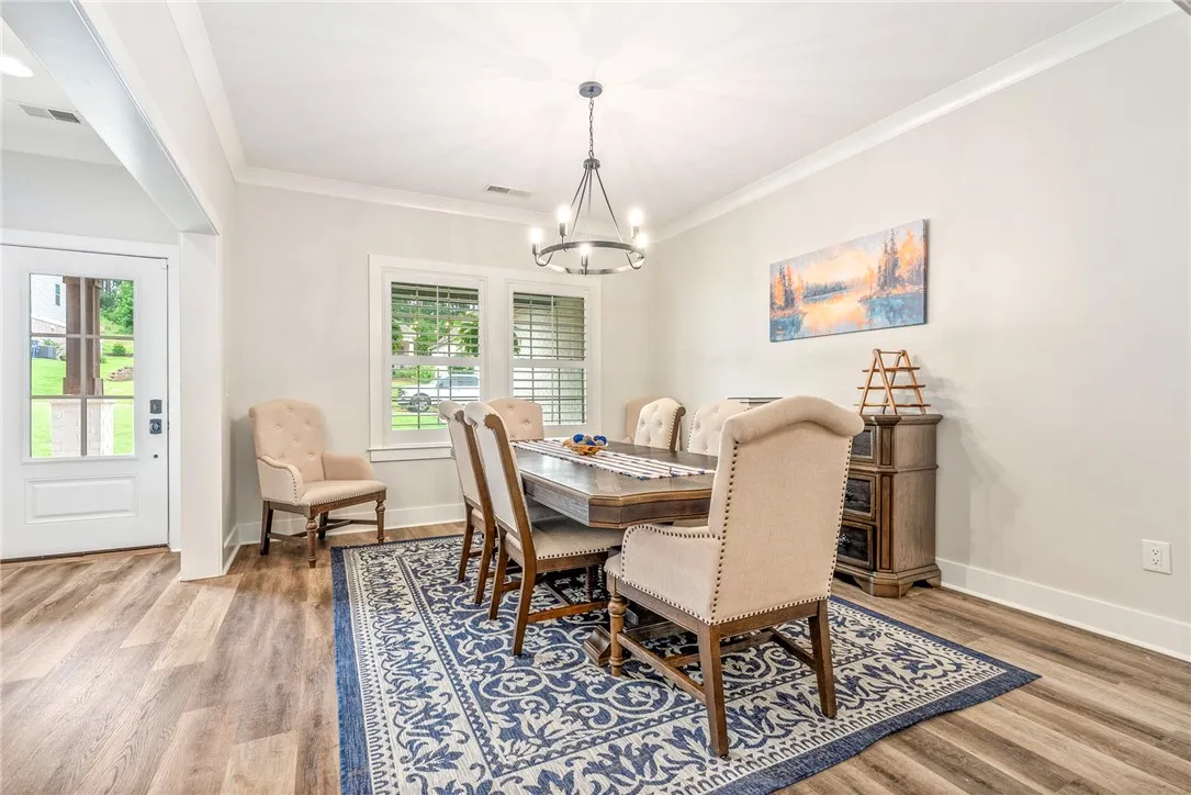 A classic dining room features crown molding, elegant lighting, and rich wood flooring.