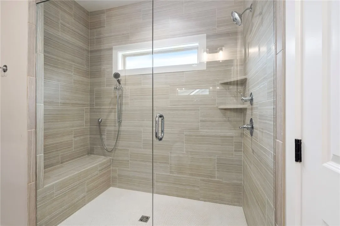 A generously proportioned shower, tiled in a serene pattern, offers a convenient built-in bench.