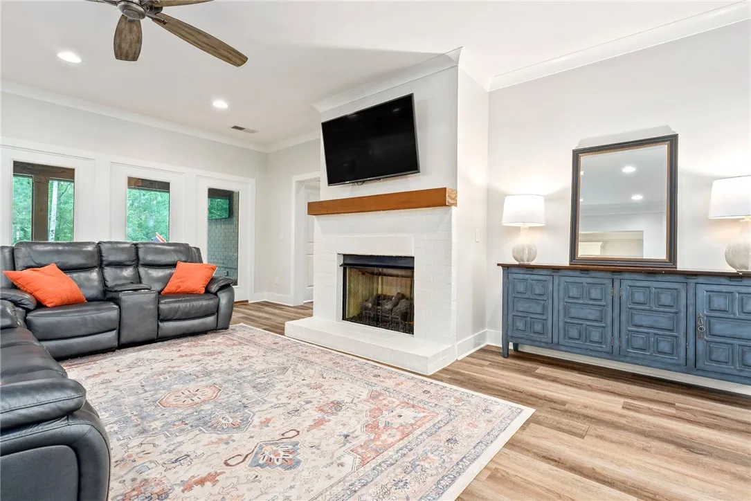 An inviting family room showcasing warm wood flooring, a fireplace, and bright overhead lighting.