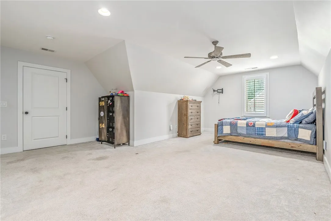 A comfortable bedroom with sloped ceilings features a ceiling fan for optimal air circulation.