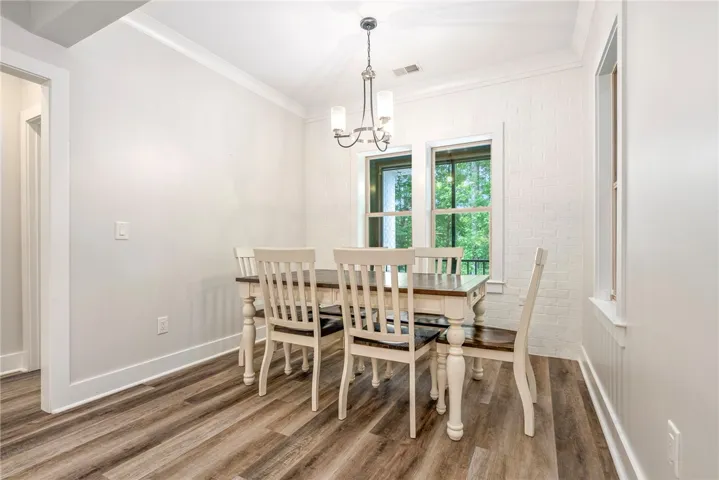 Natural light floods this dining area, featuring stylish wide plank flooring and a contemporary chandelier.
