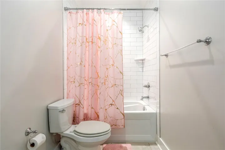 A pristine bathroom features a classic shower-over-tub design with bright white subway tile, ensuring a crisp, clean aesthetic.