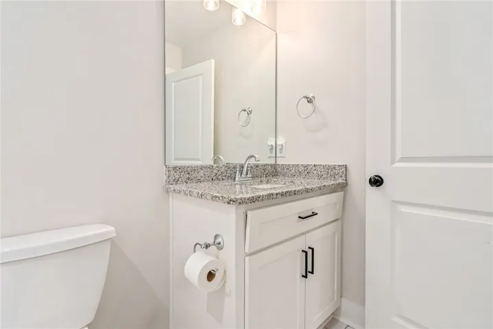 A well-appointed half-bath offers convenience and a sleek granite vanity.