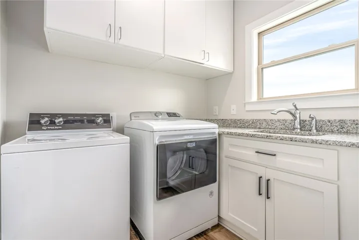 A well-appointed laundry area features convenient upper cabinetry and durable granite countertops.
