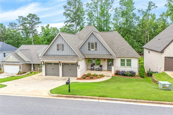 A charming residence with a covered front porch and lush green landscaping awaits.