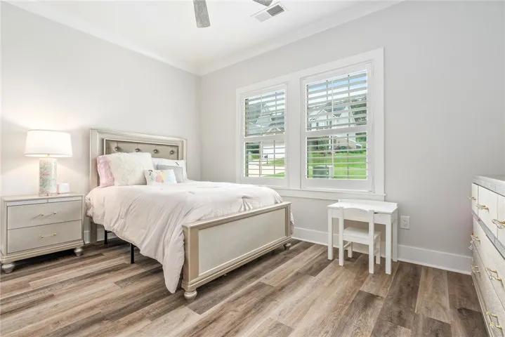 Sun-filled bedroom featuring elegant crown molding and rich hardwood flooring.
