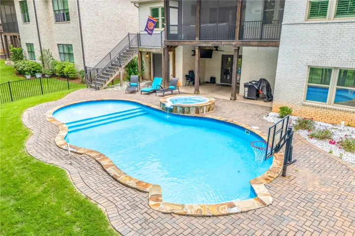 An inviting backyard oasis features a freeform pool, integrated spa, and expansive paver patio.