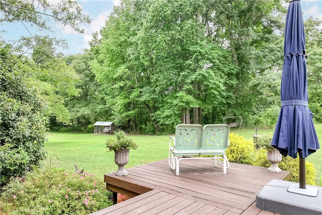 A spacious wooden deck extends into a verdant yard, offering tranquil outdoor enjoyment.