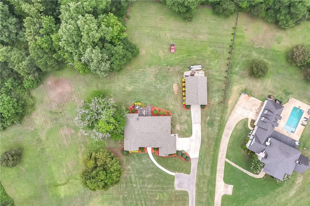 An aerial perspective showcases a sprawling estate with mature trees and a tranquil outdoor pool.